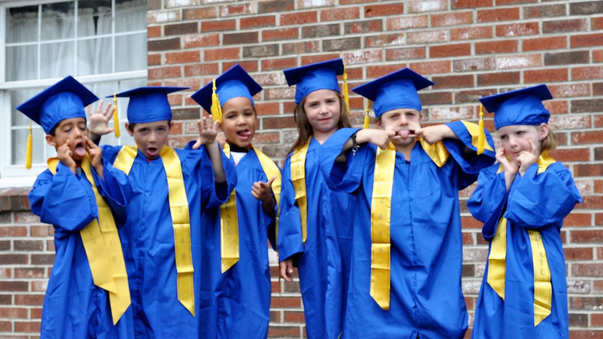 Kids wearing blue graduation caps and gowns