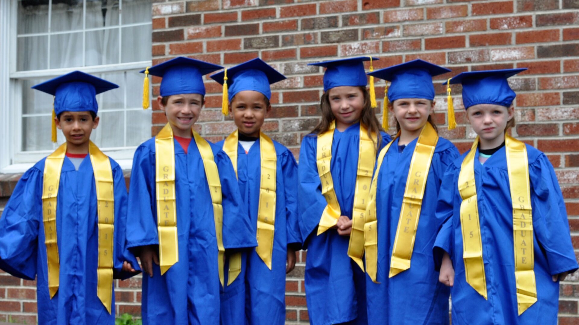 Six kids wearing blue graduation caps and gowns