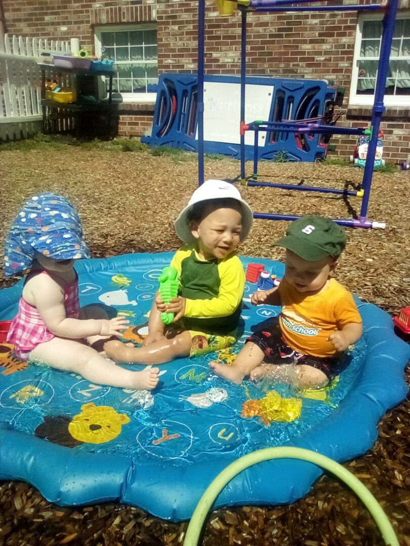 A picture of three babies sitting in inflatable pool